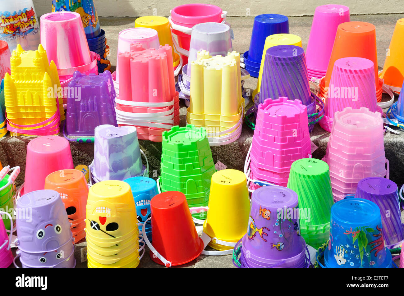 Sales display children's seaside plastic buckets - vivid colours  mixture of shapes - bright sunlight Stock Photo