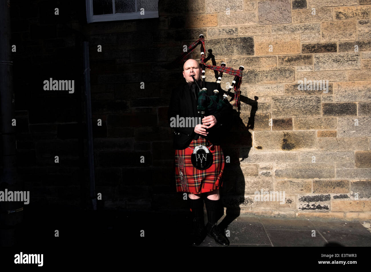A man in traditional suit plays bagpipe in Edinburgh, Scotland Stock