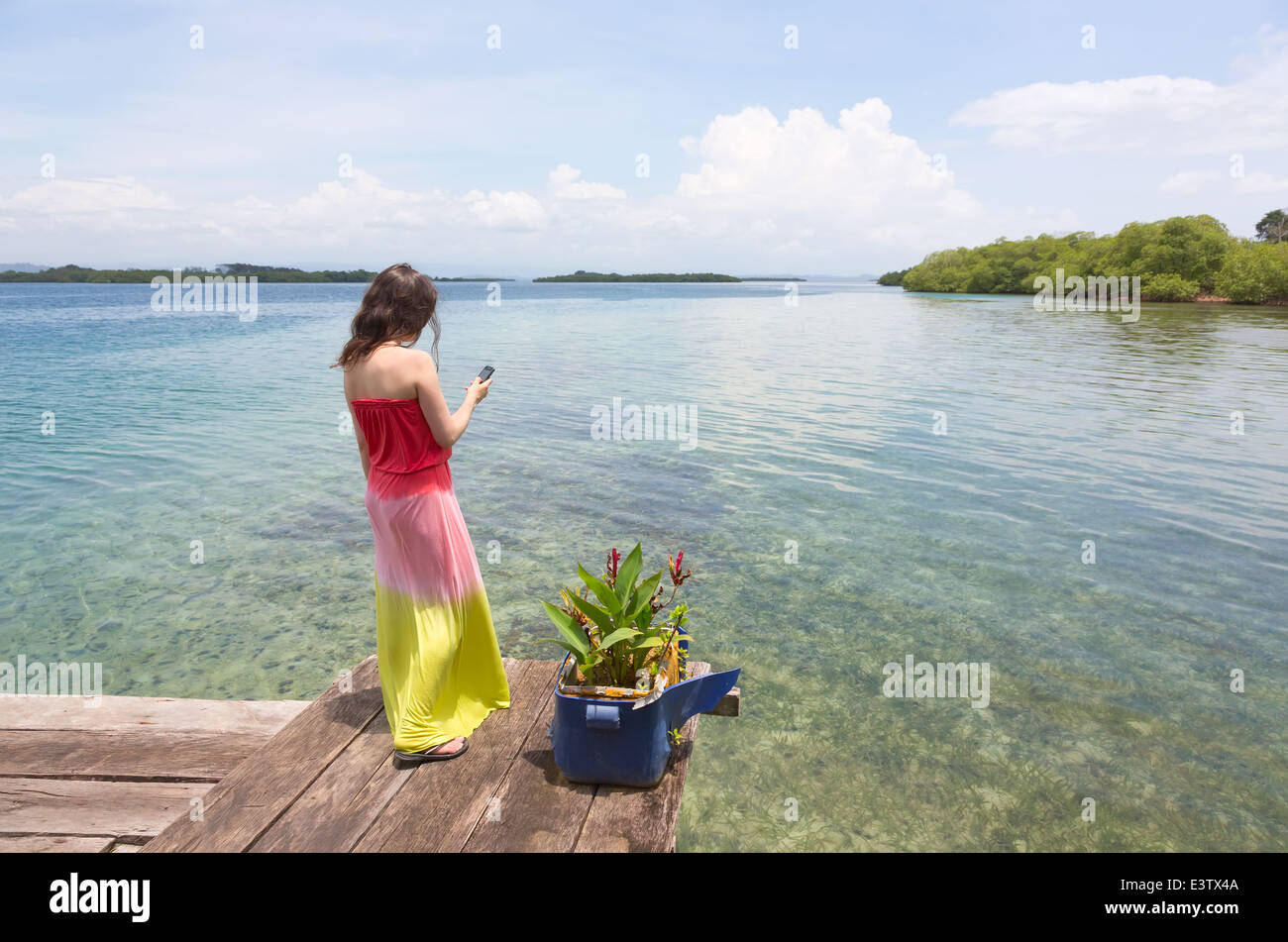 Woman looking at mobile phone at the edge of the pier, Panama Stock Photo