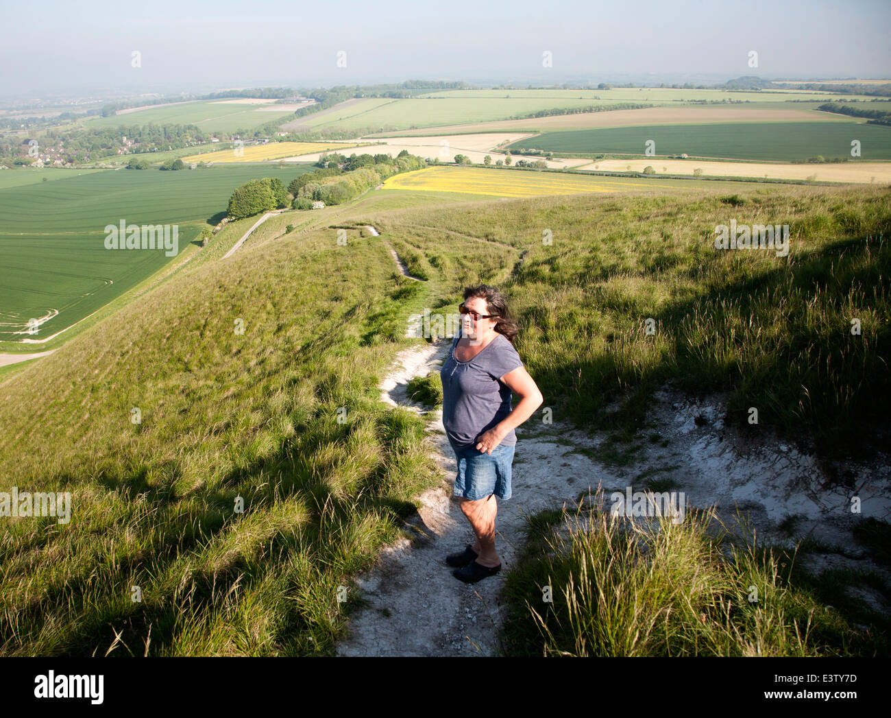 Woman walking up steep chalk scarp slope onto downland Cherhill, Wiltshire, England Stock Photo