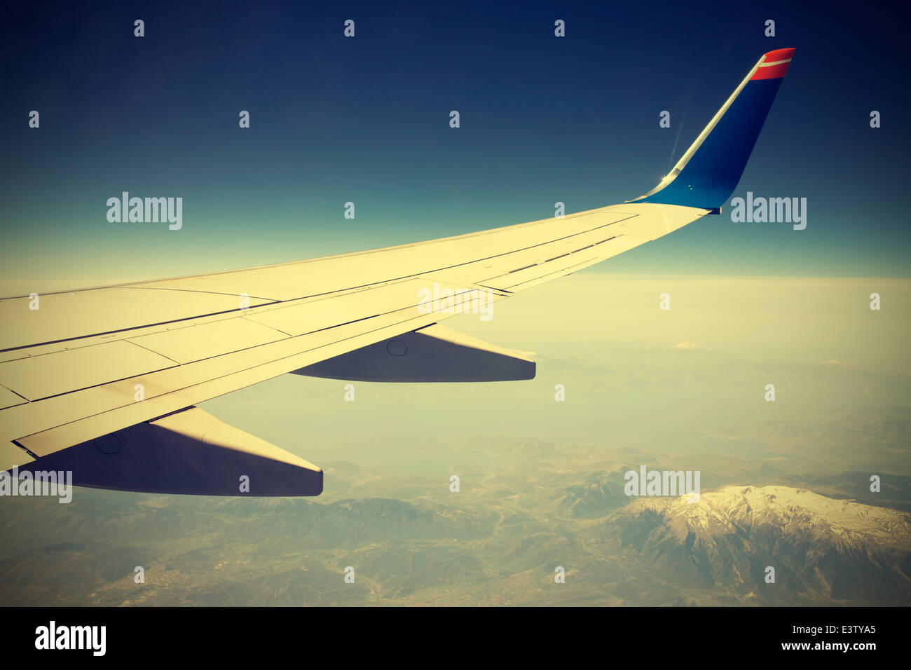 Wing of the plane on blue sky, vintage instagram retro style. Stock Photo