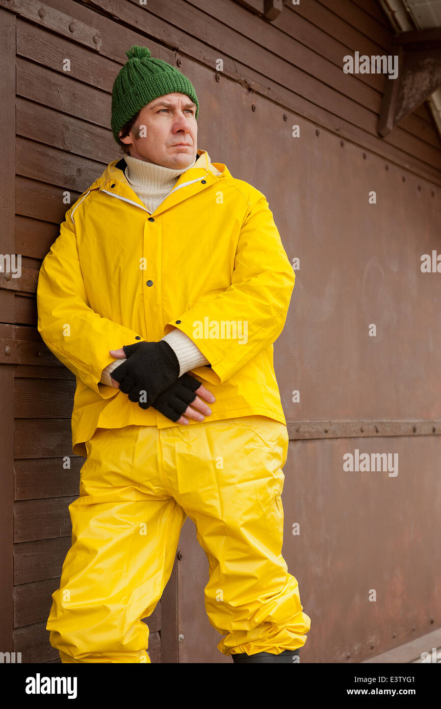 Sea fisherman, wearing bright yellow water proof overalls and leaning  against a building Stock Photo - Alamy