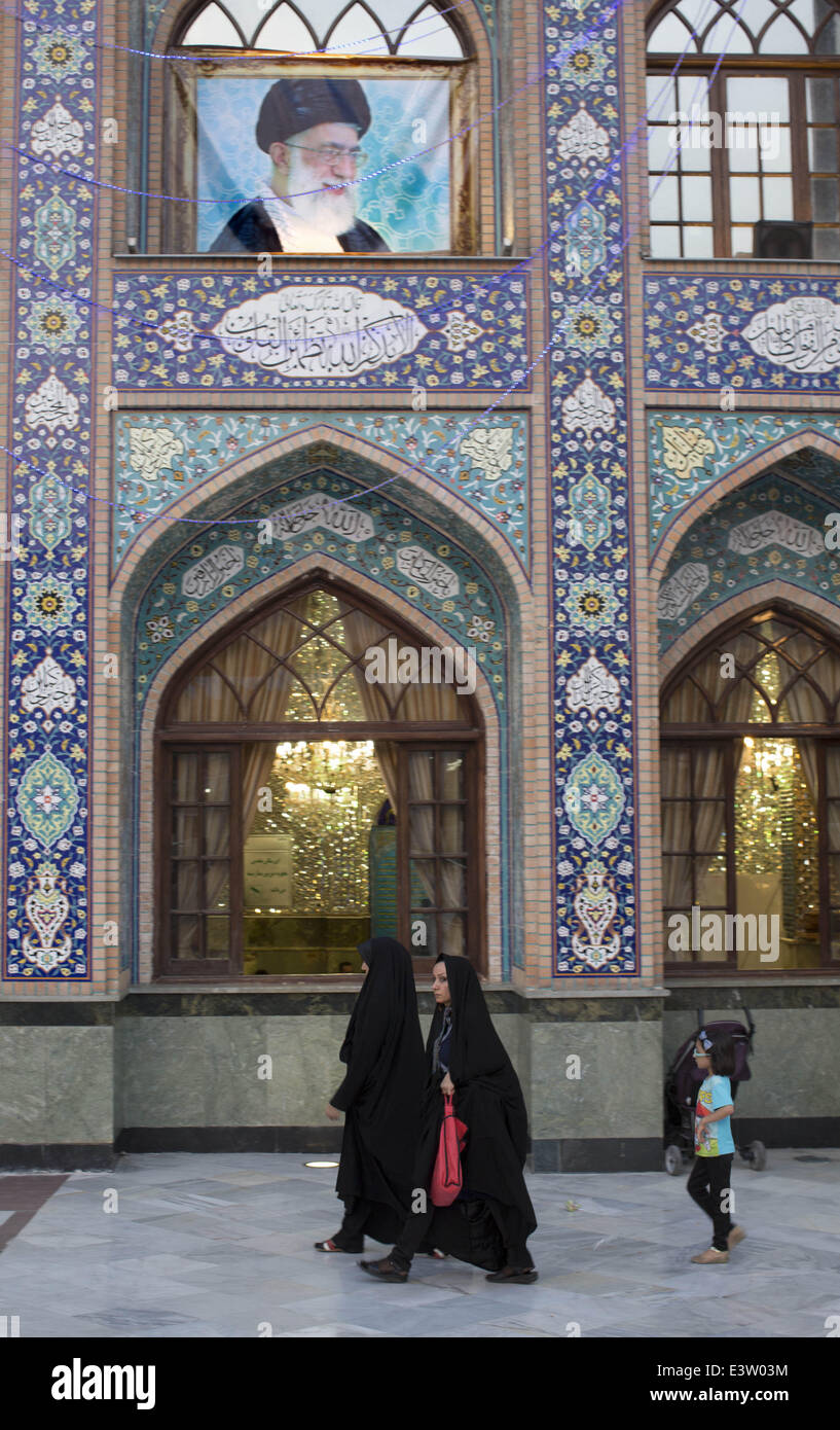 Tehran, Iran. 29th June, 2014. June 29, 2014 - Tehran, Iran - Two Iranian women and a young girl walk under a portrait of Iran's Supreme Leader Ayatollah ALI KHAMENEI as they attend a holy shrine to mark the first day of the Muslim's holy month of Ramadan. Morteza Nikoubazl/ZUMAPRESS Credit:  Morteza Nikoubazl/ZUMA Wire/ZUMAPRESS.com/Alamy Live News Stock Photo