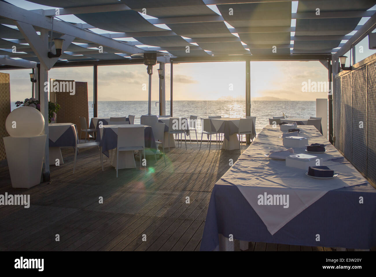'set table'cafe restaurant sunset 'lens flare' sea horizon [beach cafe] [sea restaurant] 'wooden floor' 'through window' Stock Photo