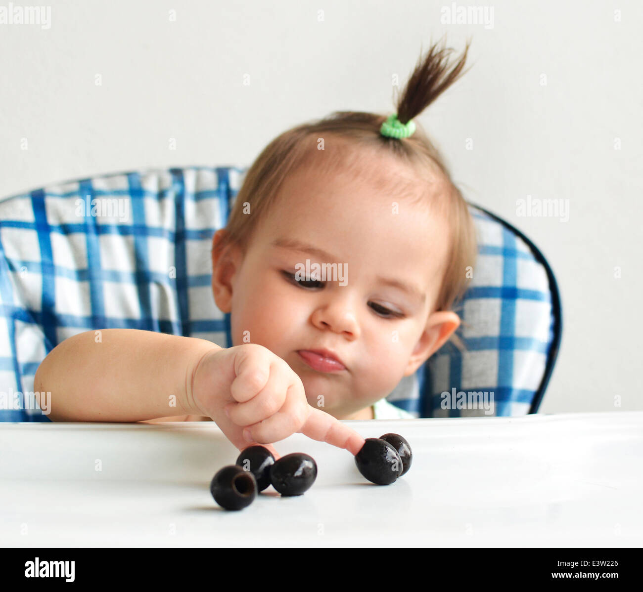 Baby in highchair playing with food Stock Photo