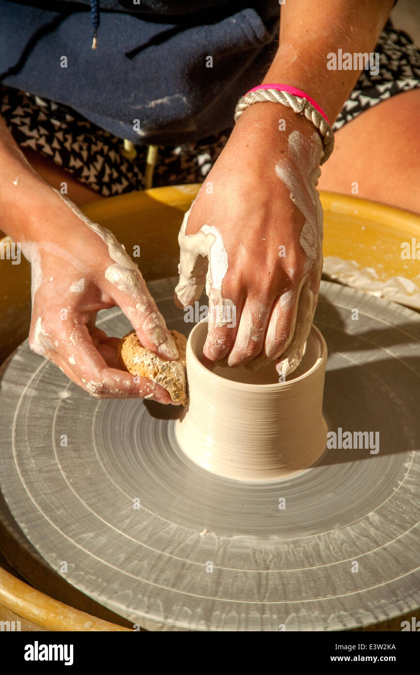 A clay pot is spun on a potter's wheel in a high school pottery class in San Clemente, CA. Note sponge to shape the moist clay. Stock Photo