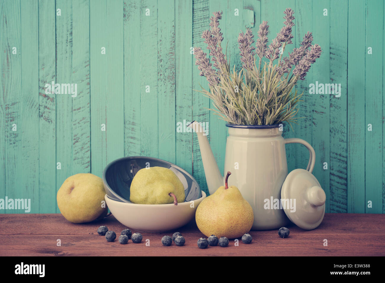 Pear in bowl with fresh blueberry and lavender flowers on wooden background Stock Photo