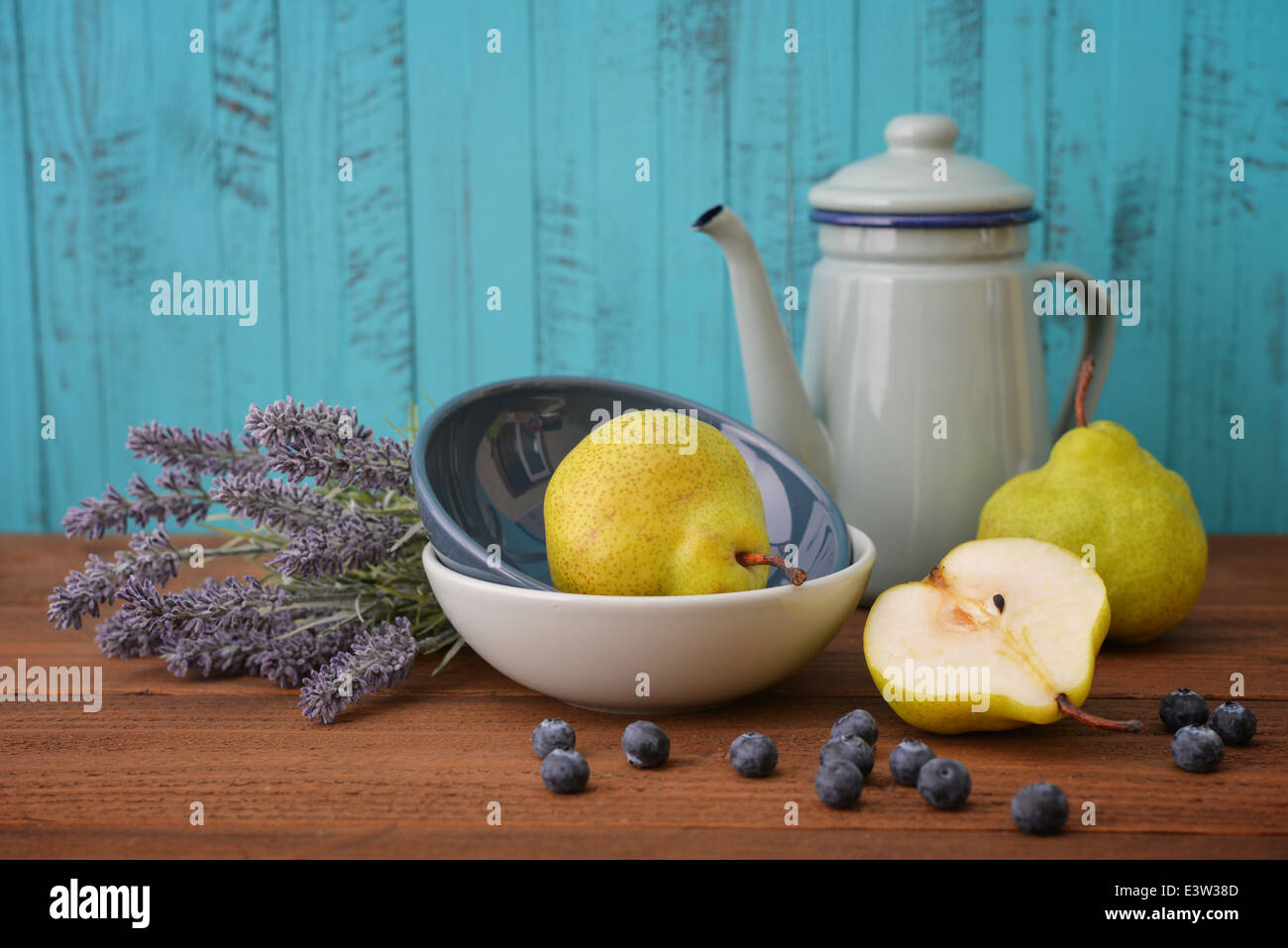 Pear in bowl with fresh blueberry and lavender flowers on wooden background Stock Photo