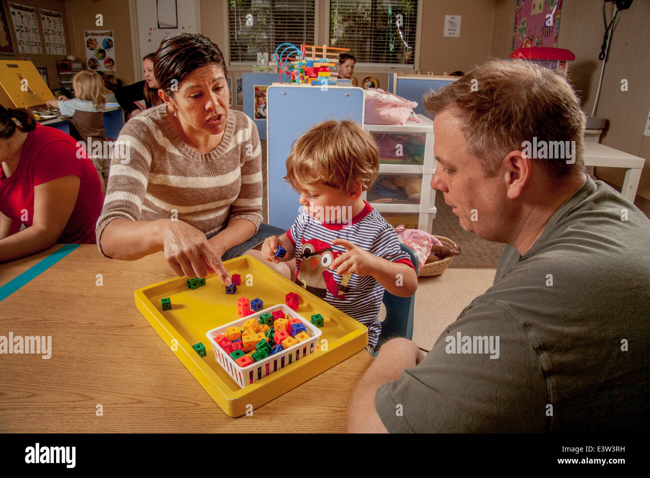 A Hispanic teacher uses visual learning aids aids with a young boy