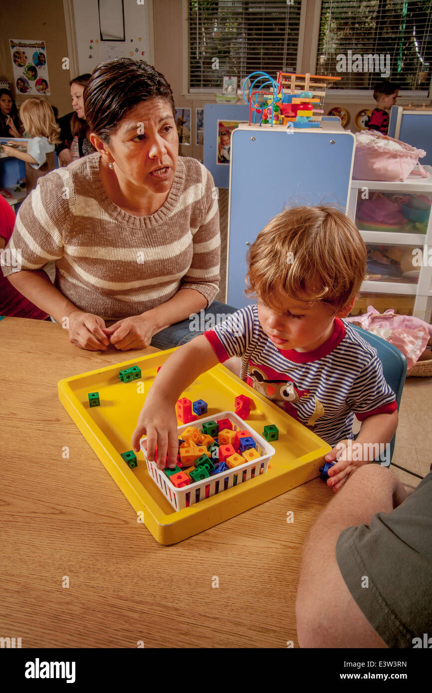 A Hispanic teacher uses visual learning aids aids with a young boy