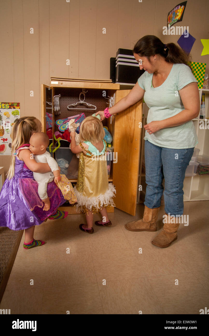 A teacher watches as a happy little girl tries out a costume at a 'Learning Link' classroom in Tustin, CA, conducting a workshop in interactive behavior. Using specially designed activities, the class teaches parents how to engage their children in meaningful play. Stock Photo