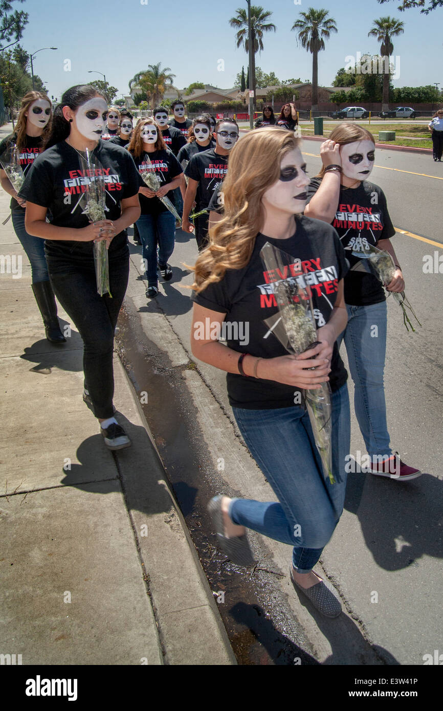 Dressed in 'Grim Reaper' costumes and carrying memorial flowers, high school students participate in a dramatization of an auto accident caused by drunk driving for the education of schoolmates in Anaheim, CA. Note grotesque makeup and 'Every Fifteen Minutes' t shirts supplied by the organization sponsoring the event. Stock Photo