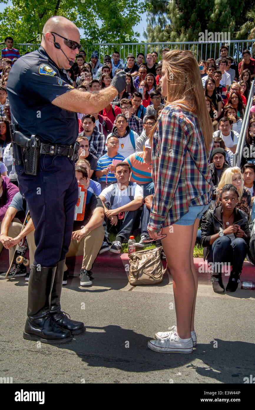 A volunteer high school girl plays the part of a driver being interrogated by a policeman in a dramatization of the danger of drunk driving for the education of schoolmates in Anaheim, CA. Note multiracial student audience in background. Stock Photo