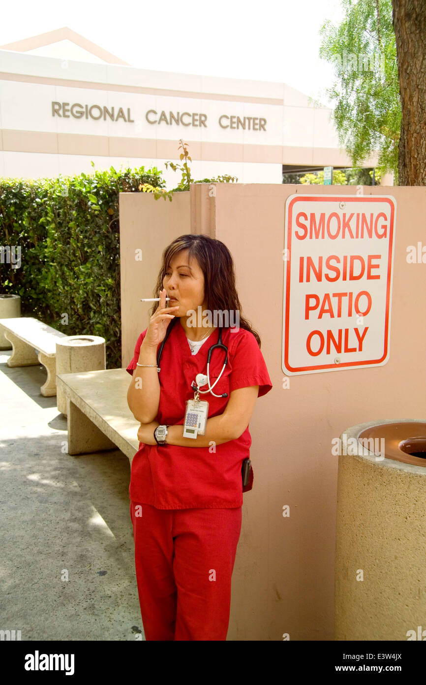 A uniformed nurse smokes cigarettes in a designated outdoor area at a