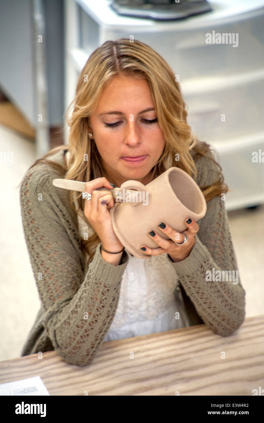 An attractive high school pottery student in San Clemente, CA, works on her class assignment, a clay mug. Stock Photo