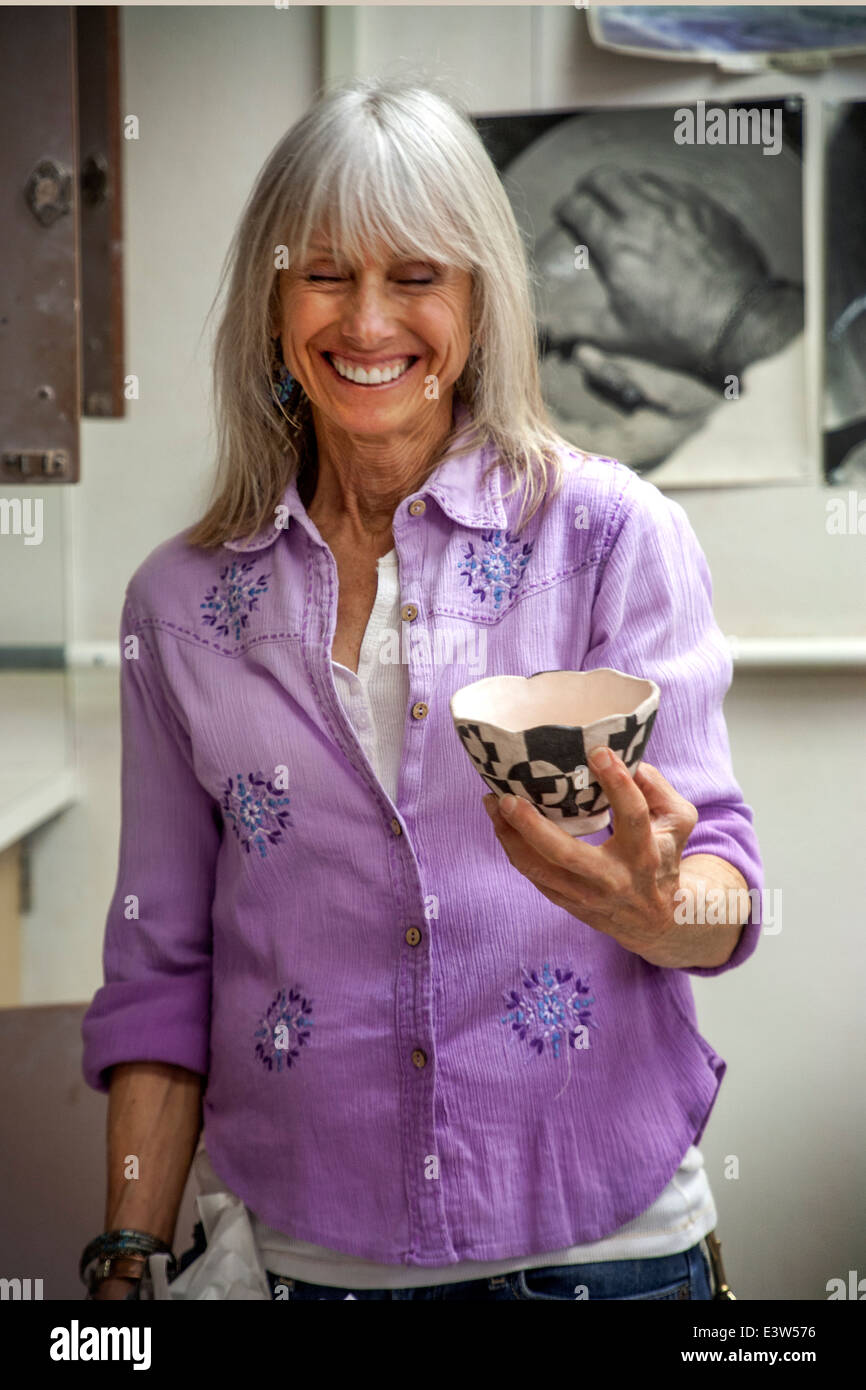 An high school pottery teacher in San Clemente, CA, laughs as she shows her students an example of quality workmanship, a clay bowl. Stock Photo