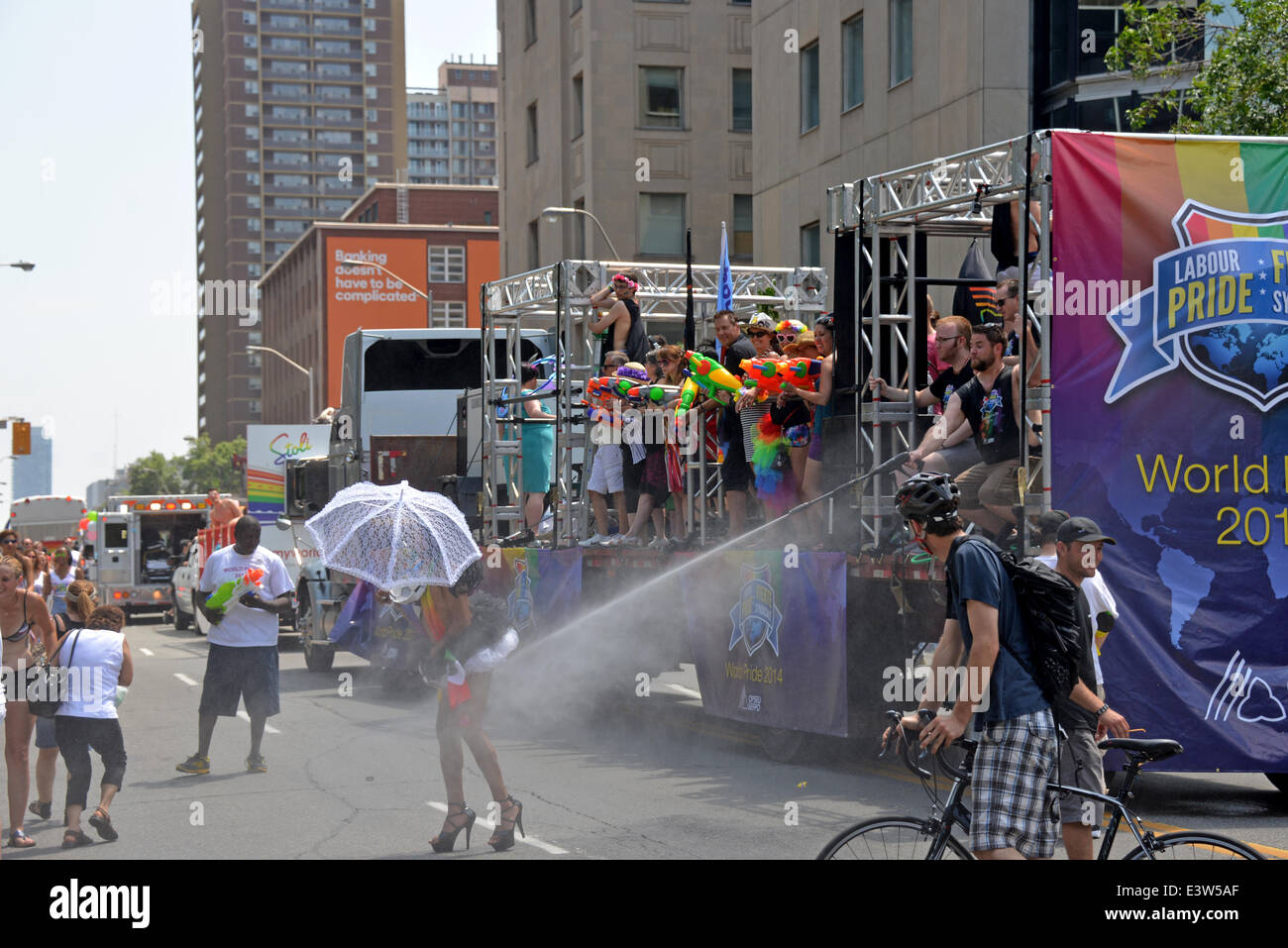 Toronto, Canada. June 29th, 2014.  WorldPride parade participant gladly accepts the spray of water from a hose in the heat. Credit:  Paul McKinnon/Alamy Live News Stock Photo