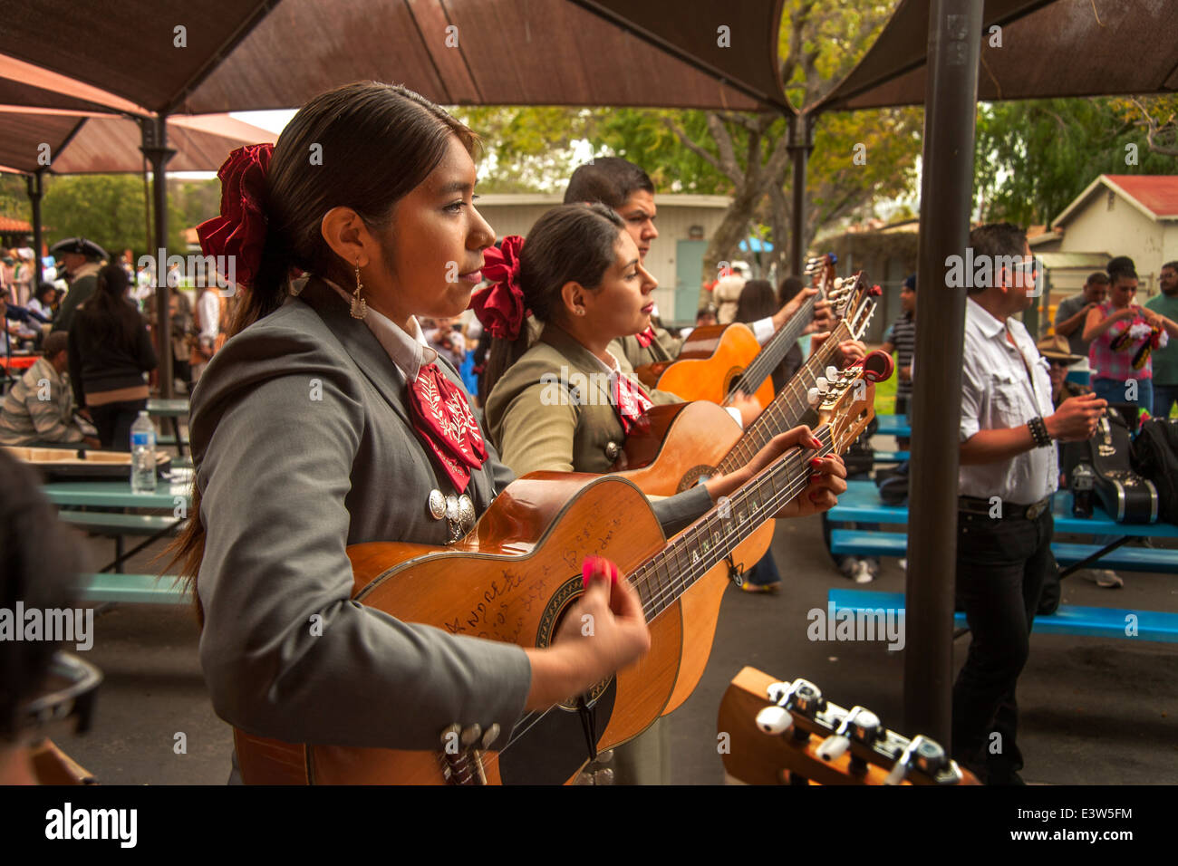 A costumed female mariachi band practices their guitars before