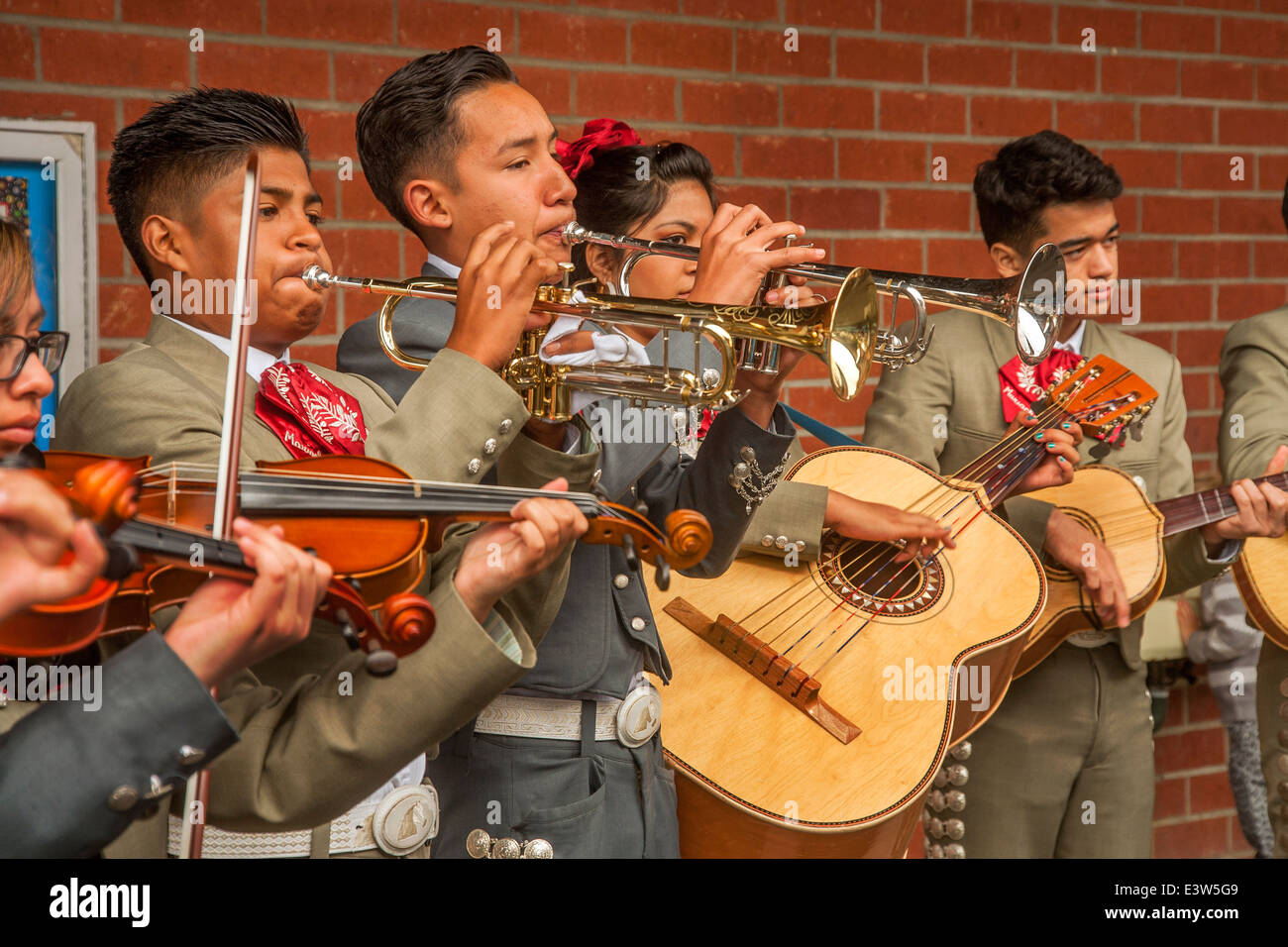 A costumed mariachi band practices their guitars, trumpets, and violins