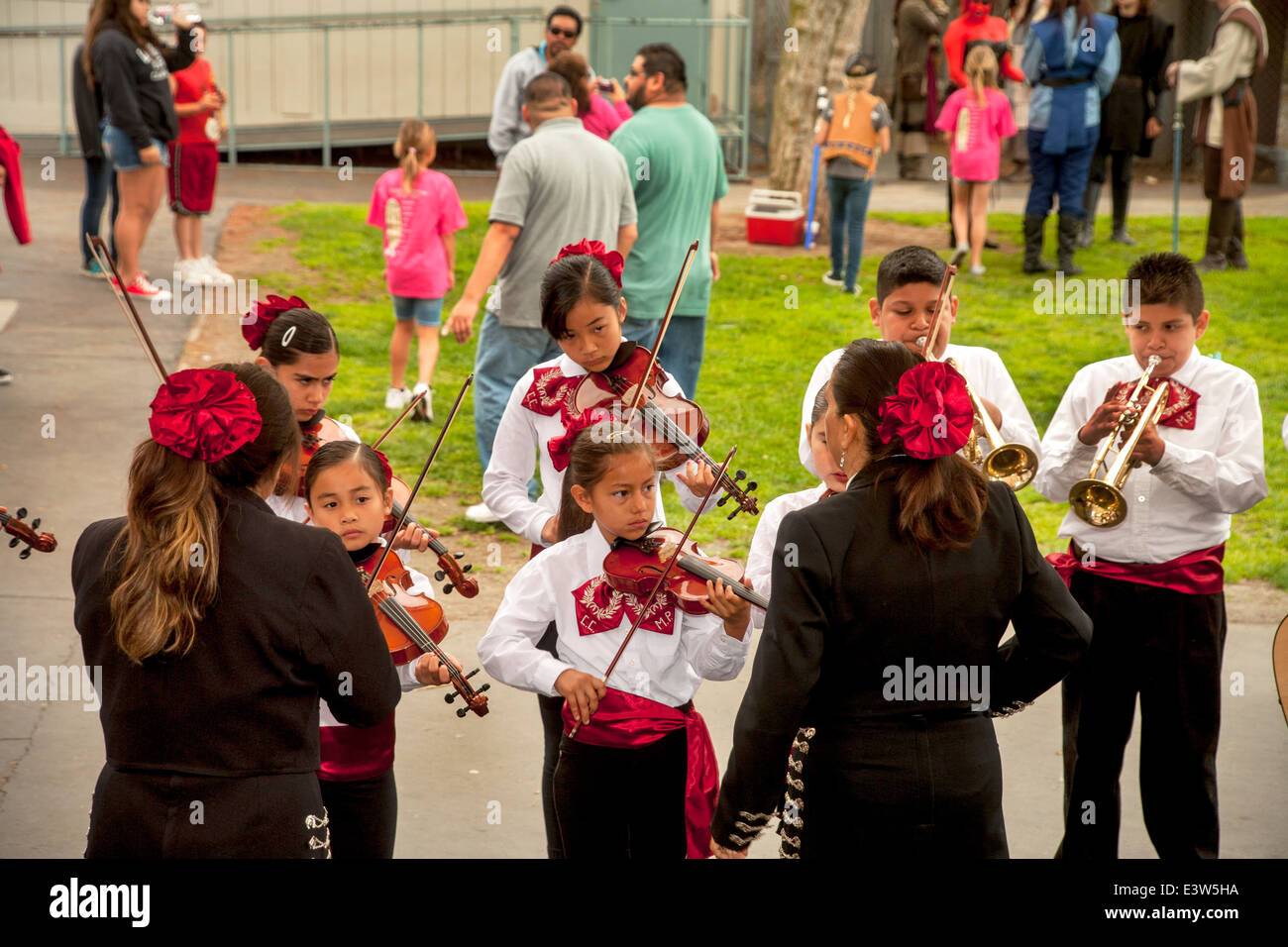 A costumed mariachi band of young people practices their guitars and