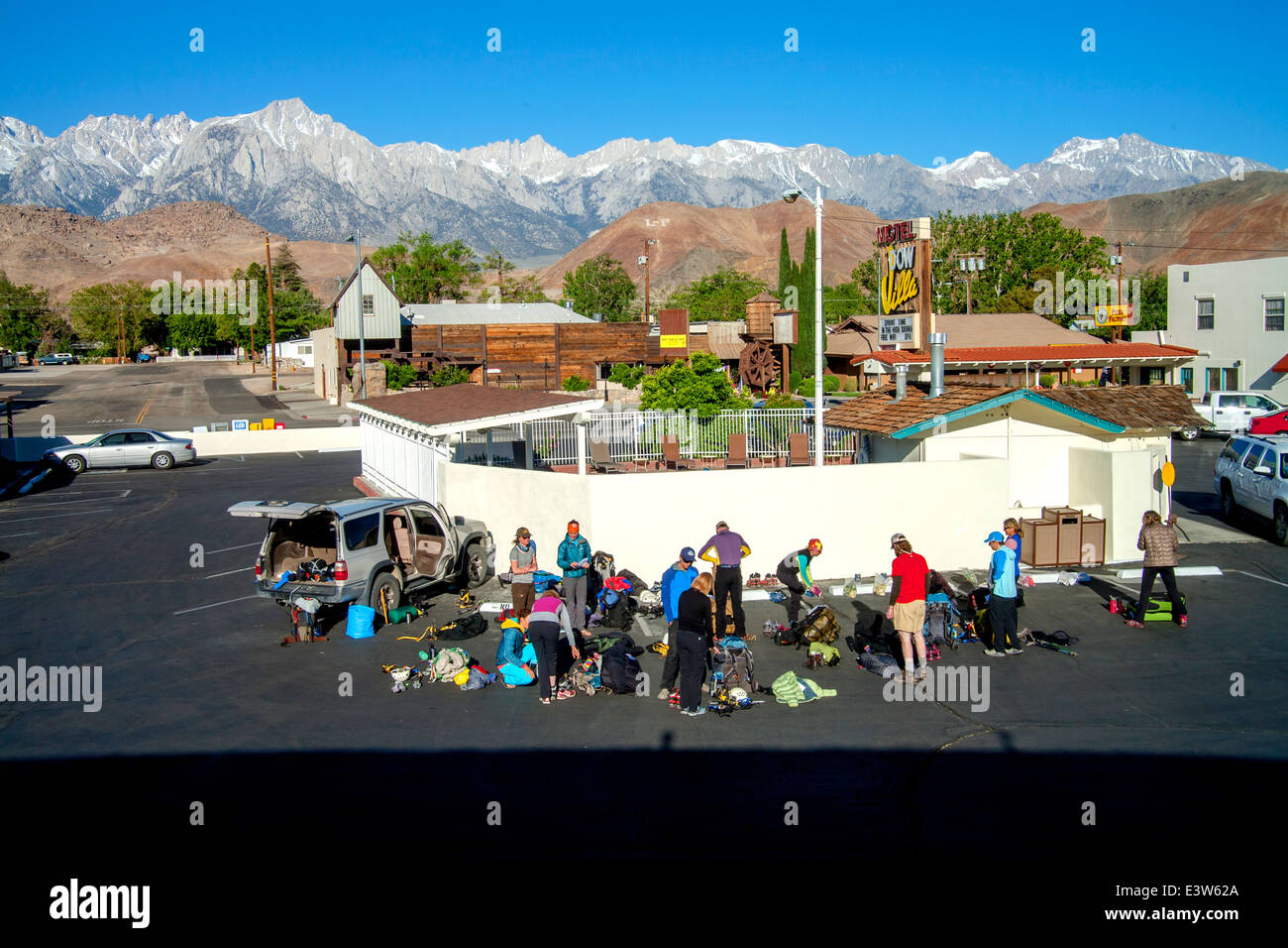 A rock climbing club gathers to organize their equipment before beginning an expedition in Lone Pine, CA. Note Sierra Nevada mountains in background. Stock Photo