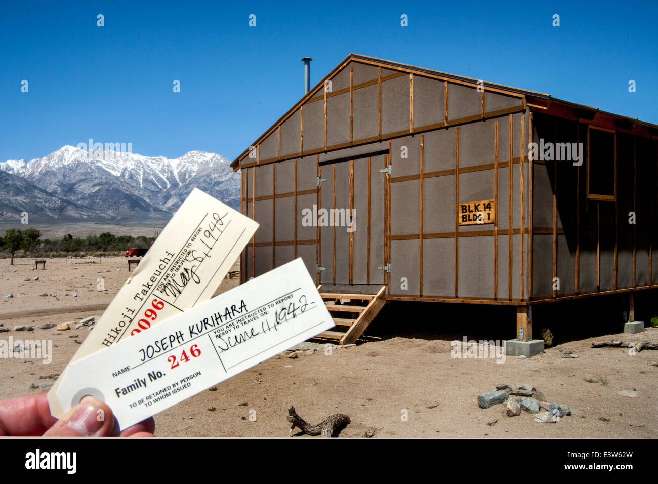 Replicas of two 1942 prisoner identification tags are juxtaposed with a re-created barracks  at the Manzanar prison camp outside Lone Pine, CA, where Japanese Americans were unjustly imprisoned during World War II. Note Sierra Nevada mountains in background. Stock Photo