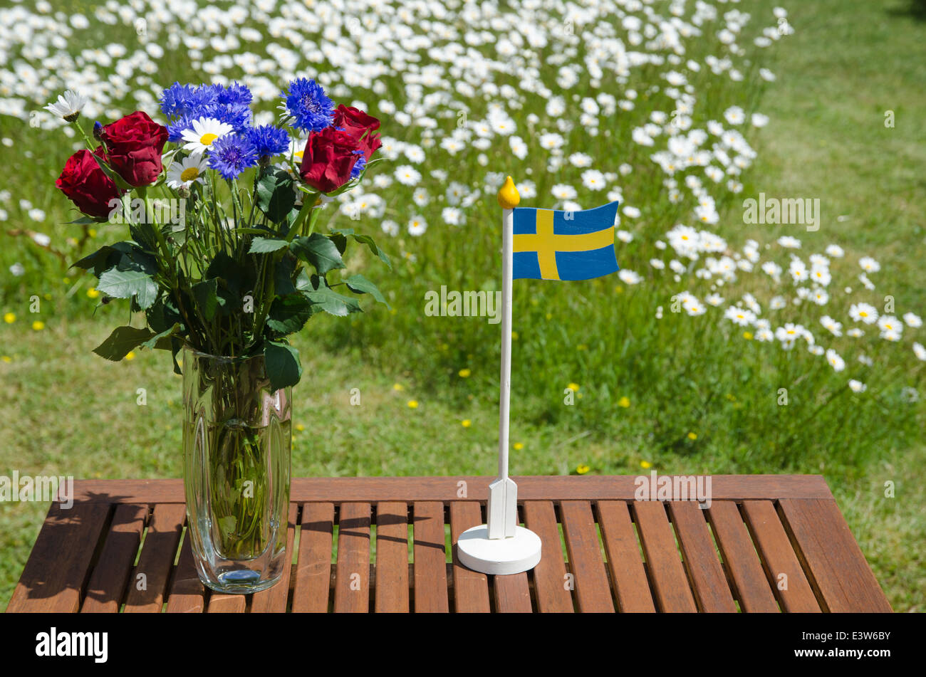 Table with summer flowers and a swedish flag in a garden with daisies Stock Photo