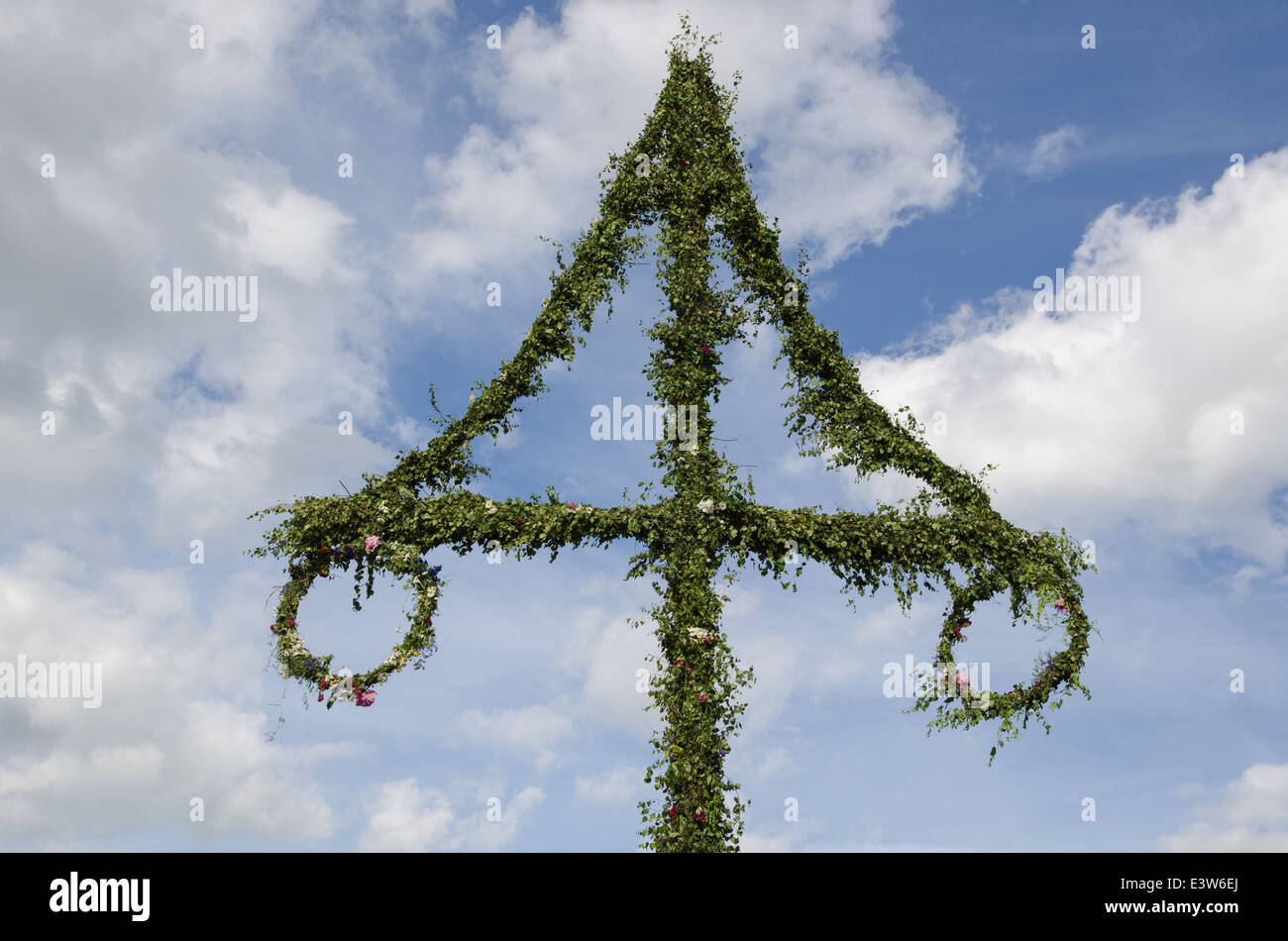 Top of a swedish midsummer pole at blue sky with white clouds Stock Photo