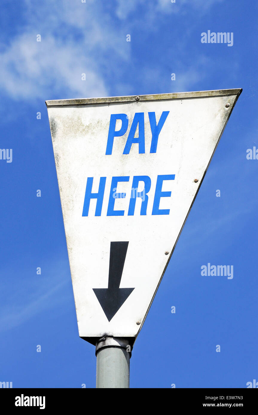 Pay here sign in a white triangle against a blue sky, Bourton on the Water, Gloucestershire, England, UK, Western Europe. Stock Photo