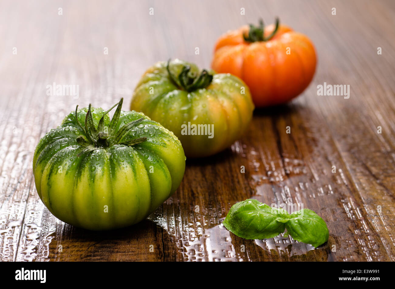 Italian tomatoes with basil on a wooden table Stock Photo - Alamy