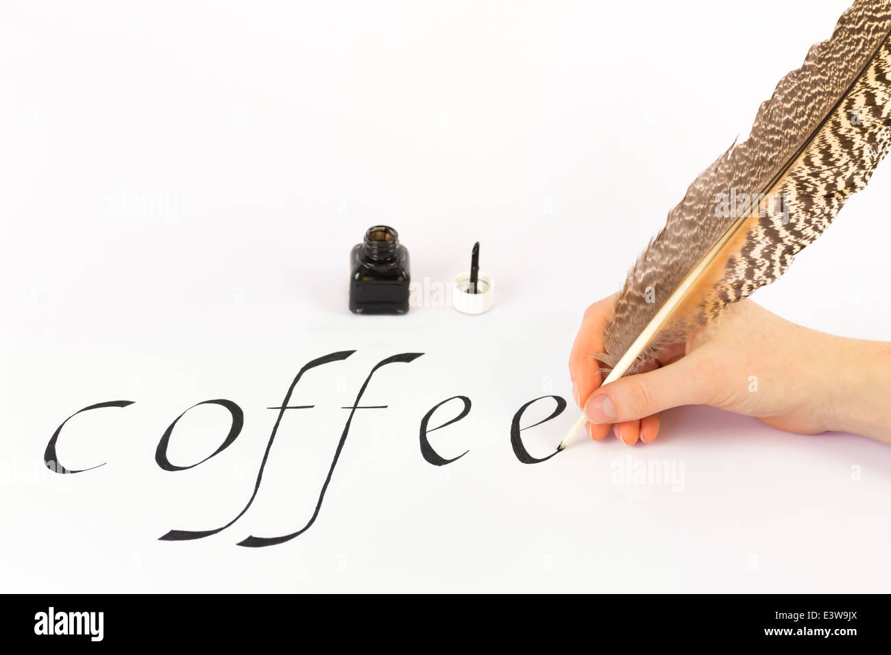 Hand writing the word COFFEE with feather Stock Photo
