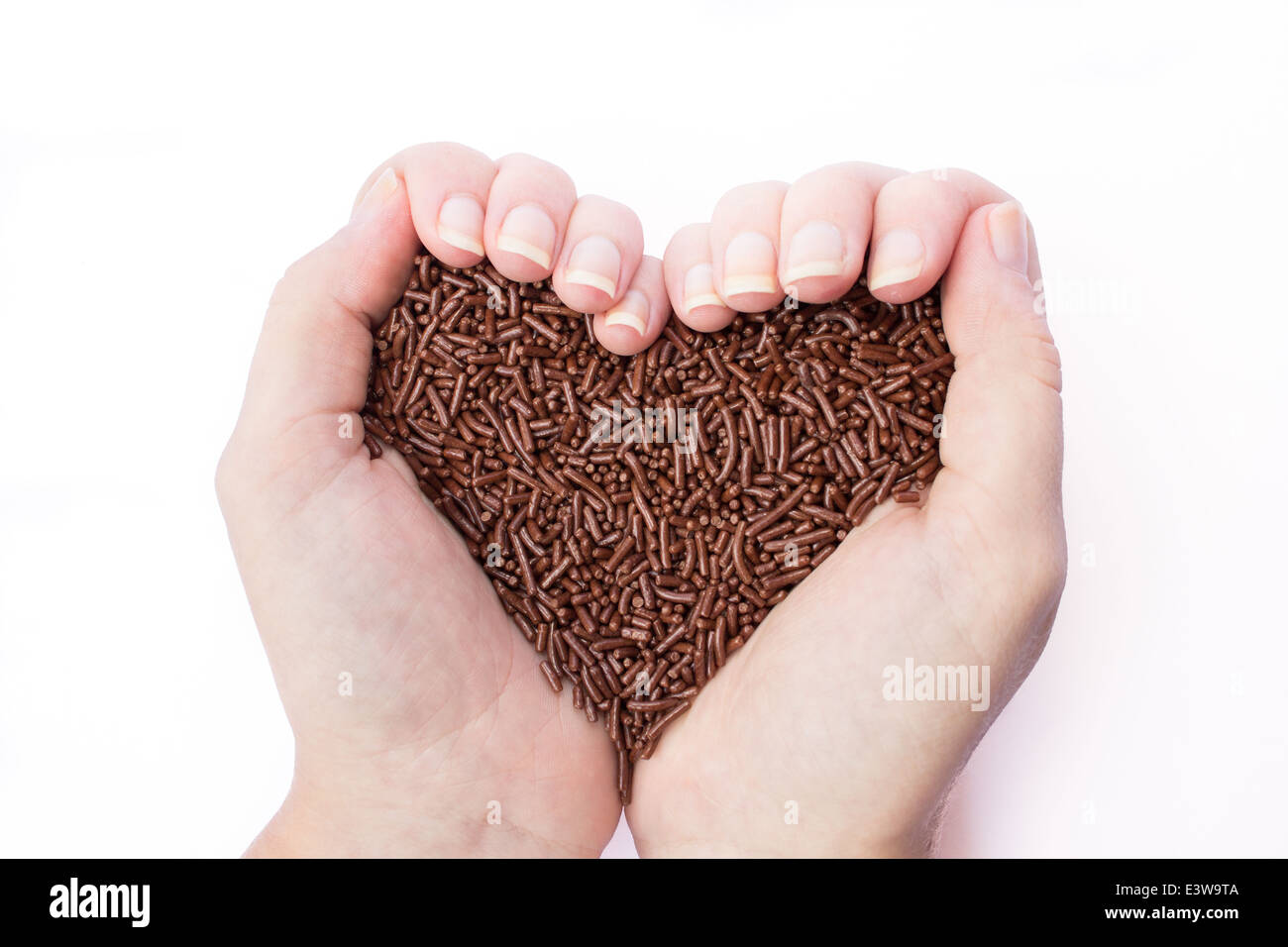 Two female hands holding chocolate sprinkles in shape of heart symbol Stock Photo