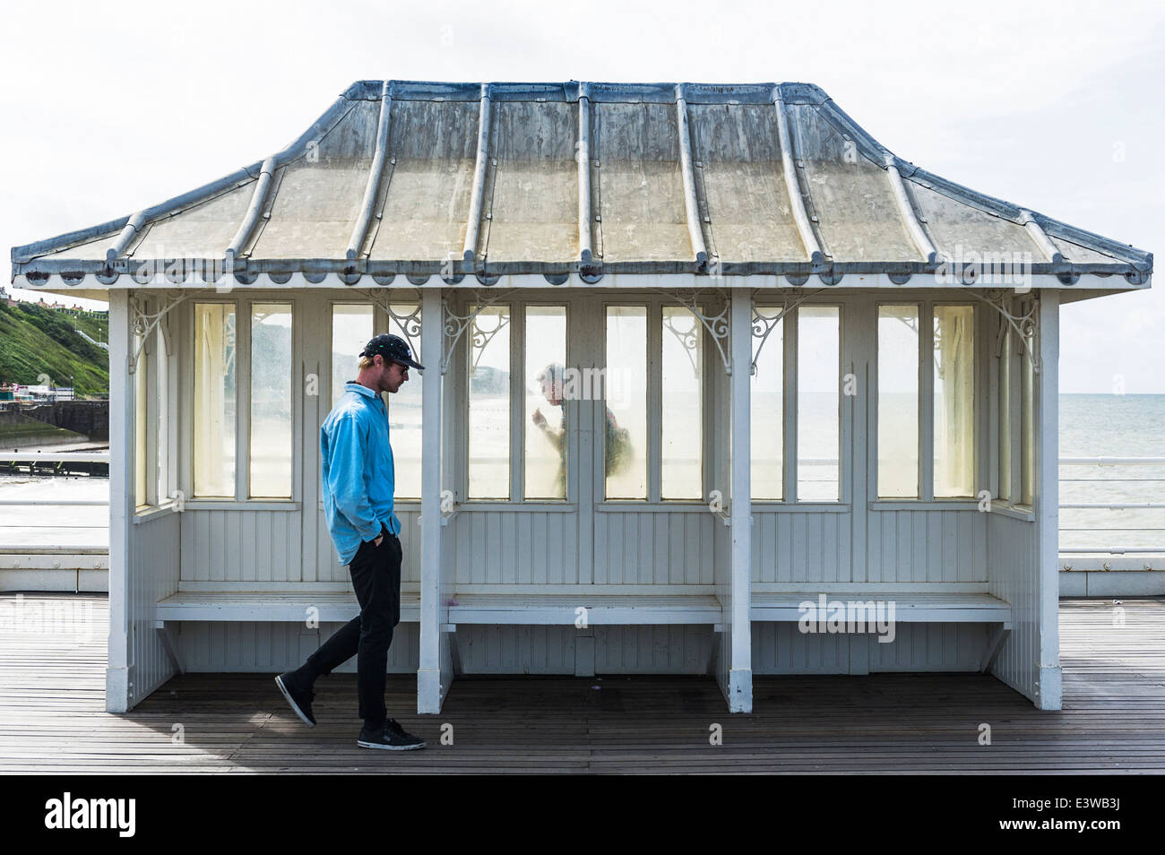 People walking past a shelter on Cromer Pier. Stock Photo