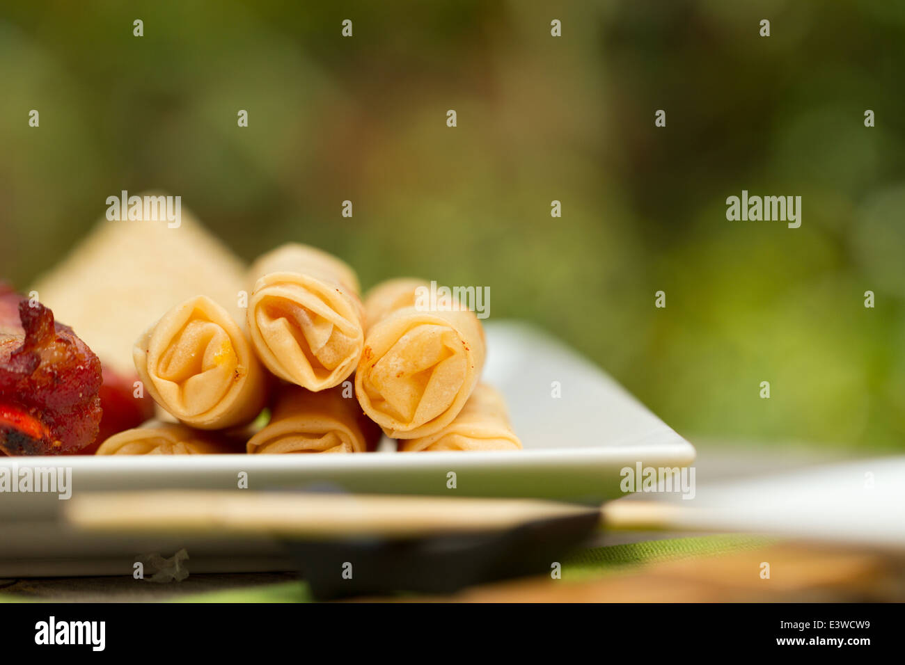 Chinese food appetizers on a platter outside, including spring rolls