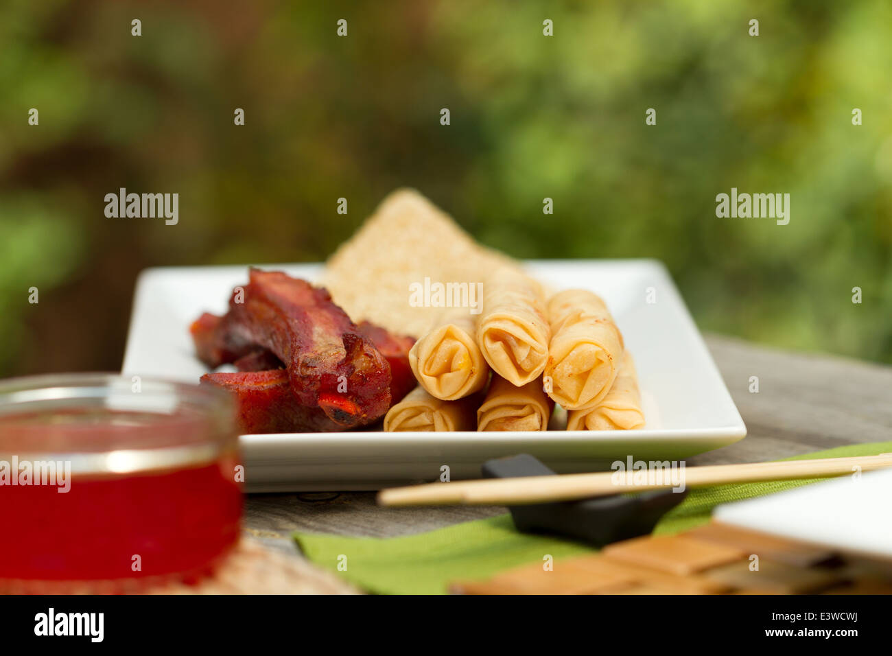 Chinese food appetizers on a platter outside, including spring rolls