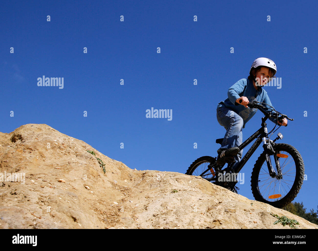 A young boy wearing a helmet rides his BMX bicycle in woodland in Hampshire, England Stock Photo