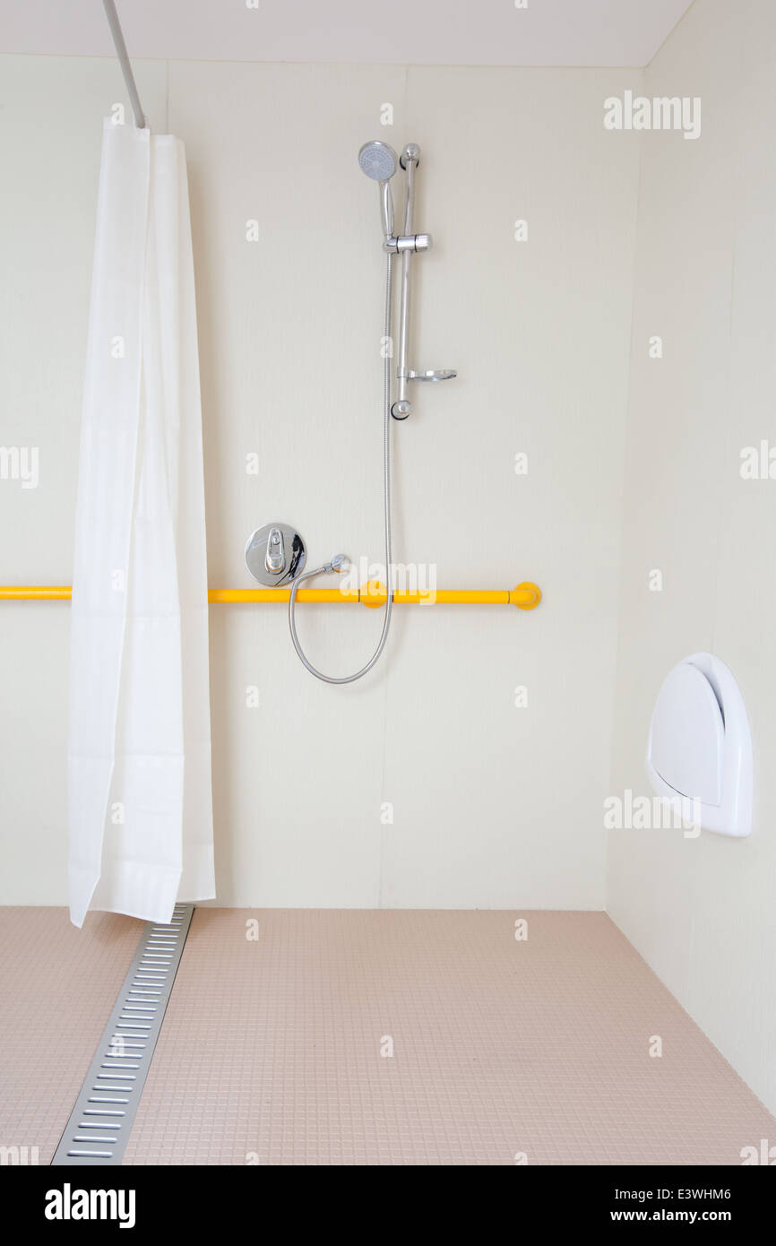 Disabled shower room with seat and rail. with white and chrome fixtures. Stock Photo
