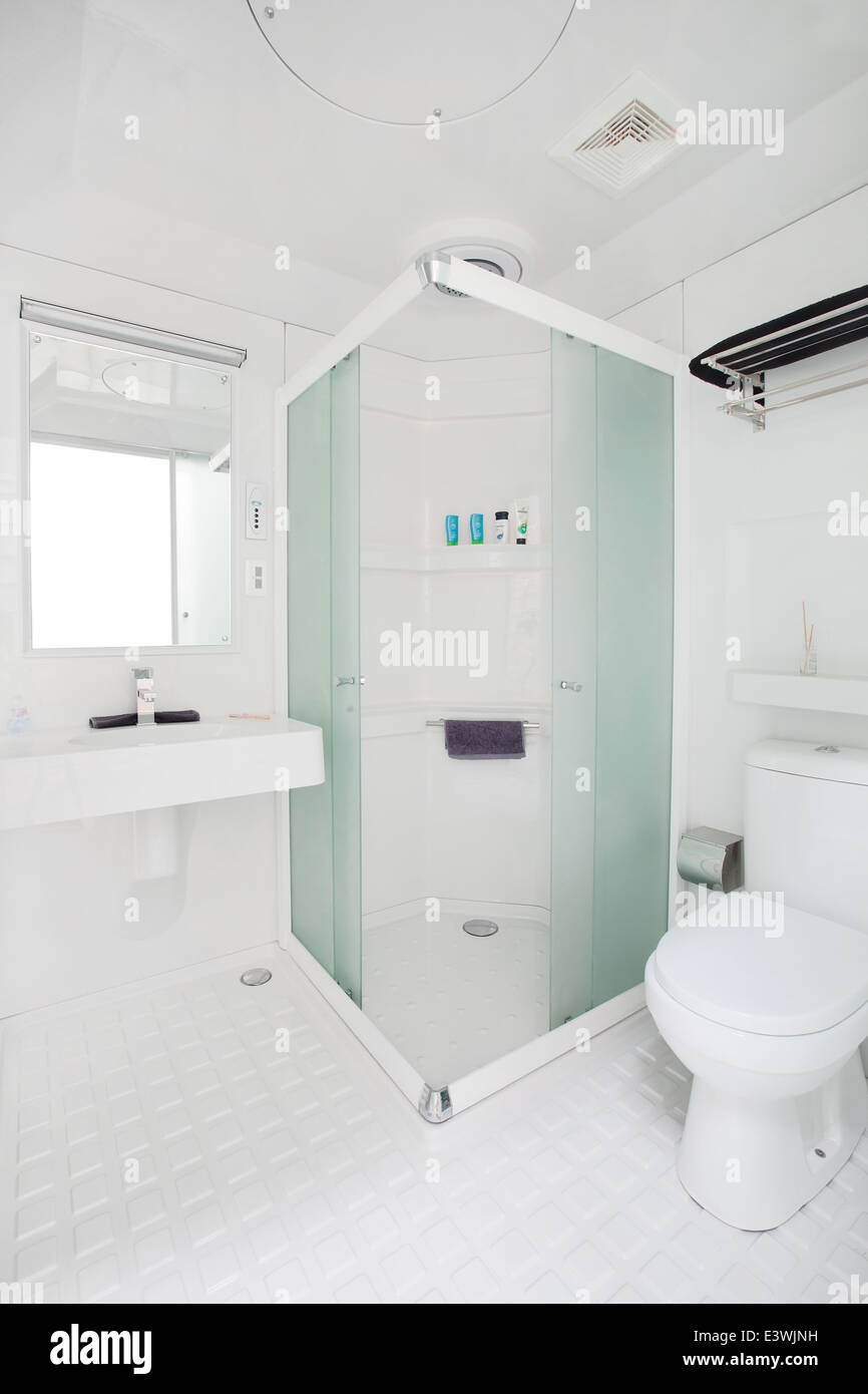 clean compact modern bathroom new commercial. including - mirror, shower, sink, toilet, tiles, cubical, storage. no people. Stock Photo
