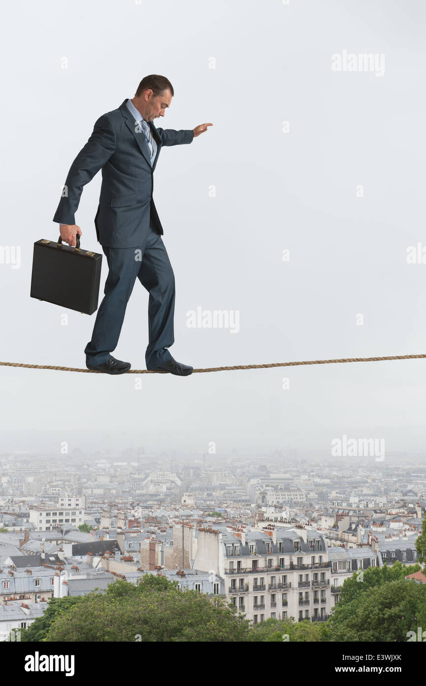 businessman walking across a tightrope or highwire balancing above a city Stock Photo