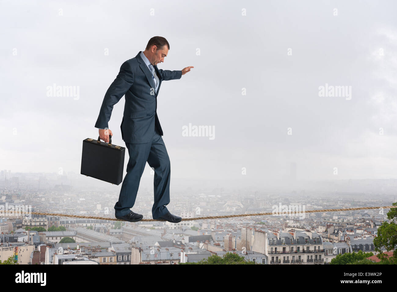 businessman walking across a highwire or tightrope balancing above the city Stock Photo