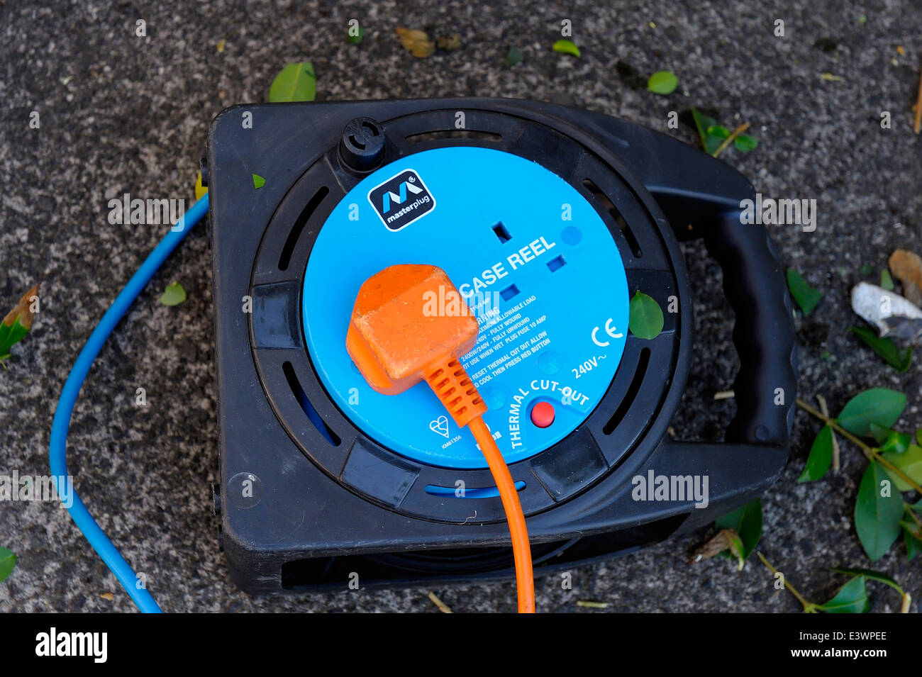 An orange plug lead plugged into a blue extension cable reel Stock