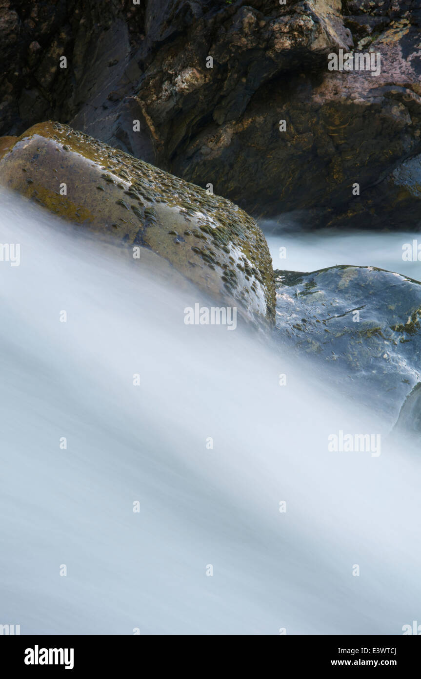 Long exposure of water flowing in a stream over rocks down to the St. Lawrence river near Gaspé, Quebec. Stock Photo