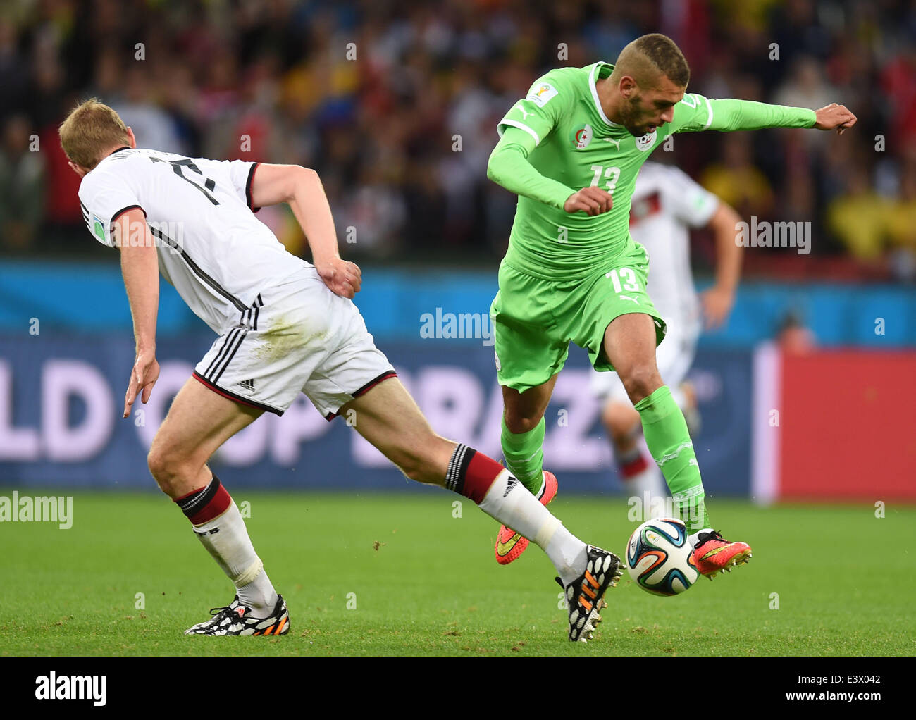 Porto Alegre, Brazil. 30th June, 2014. Germany's Per Mertesacker (L) vies with Algeria's Islam Slimani during a Round of 16 match between Germany and Algeria of 2014 FIFA World Cup at the Estadio Beira-Rio Stadium in Porto Alegre, Brazil, on June 30, 2014. Credit:  Li Ga/Xinhua/Alamy Live News Stock Photo