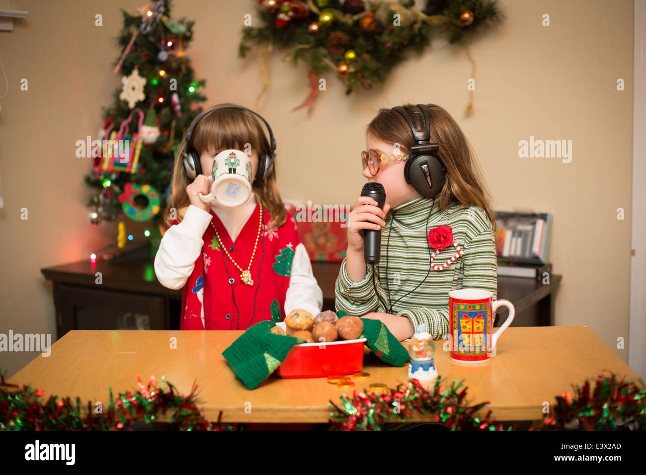 Two little girls with donut holes running a radio show on Christmas. Stock Photo