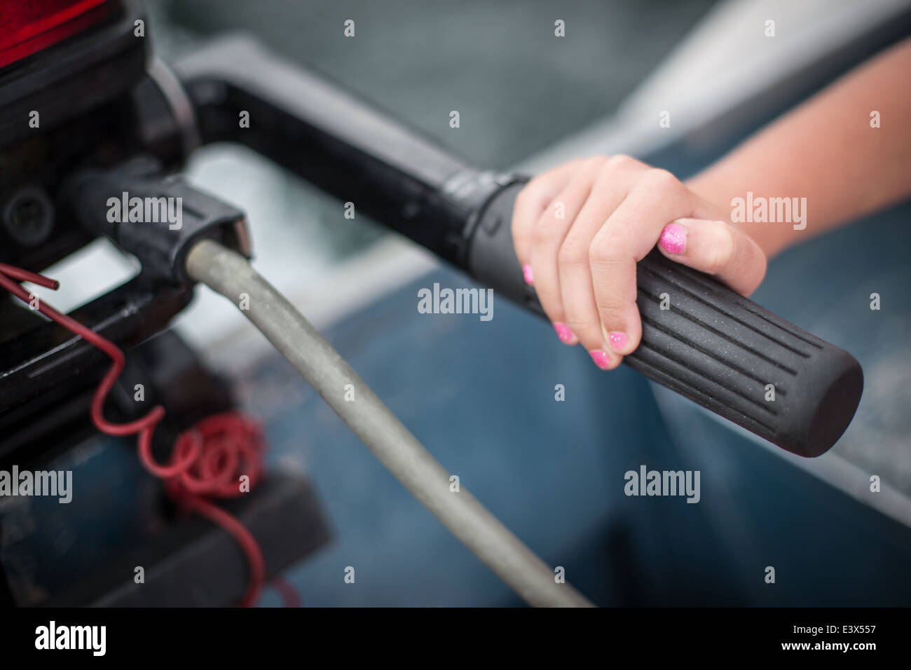Little girl's hand with pink nail polish on boat throttle. Stock Photo