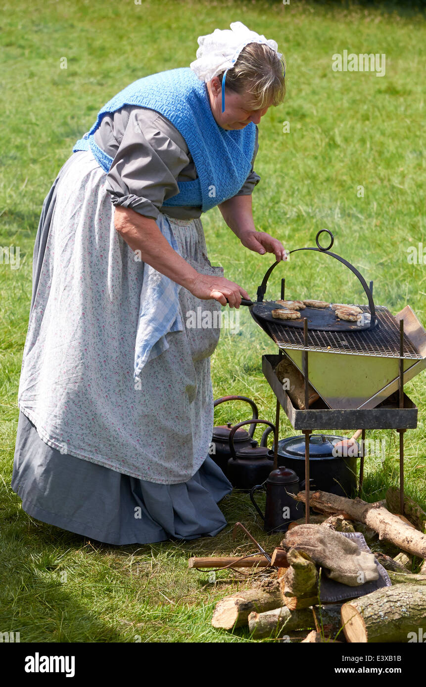 Woman in 1860's dress cooking damper on a Union Army camp kitchen of the period at a Civil War event. Stock Photo