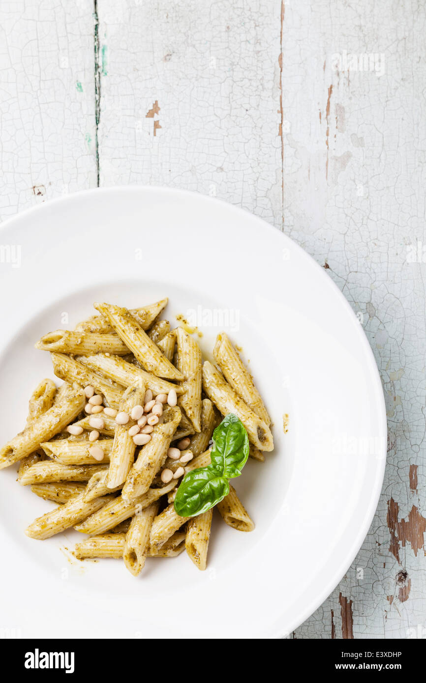 Pasta Penne with pesto sauce and pine nuts on wooden background Stock Photo