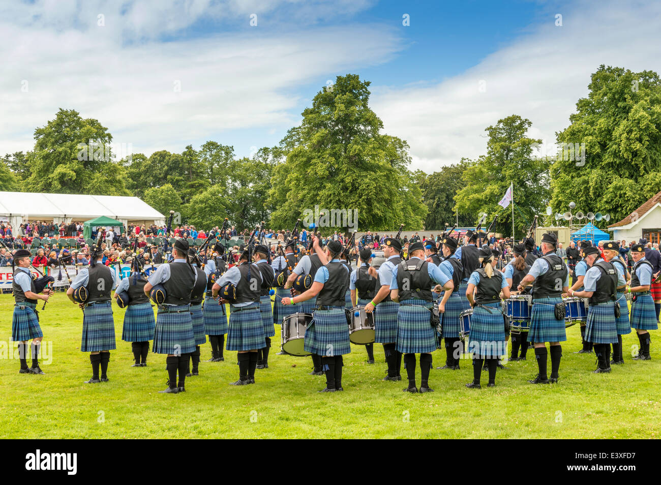 PIPE BAND WITH BLUE AND GREEN KILTS PLAYING BEFORE SPECTATORS AT FORRES