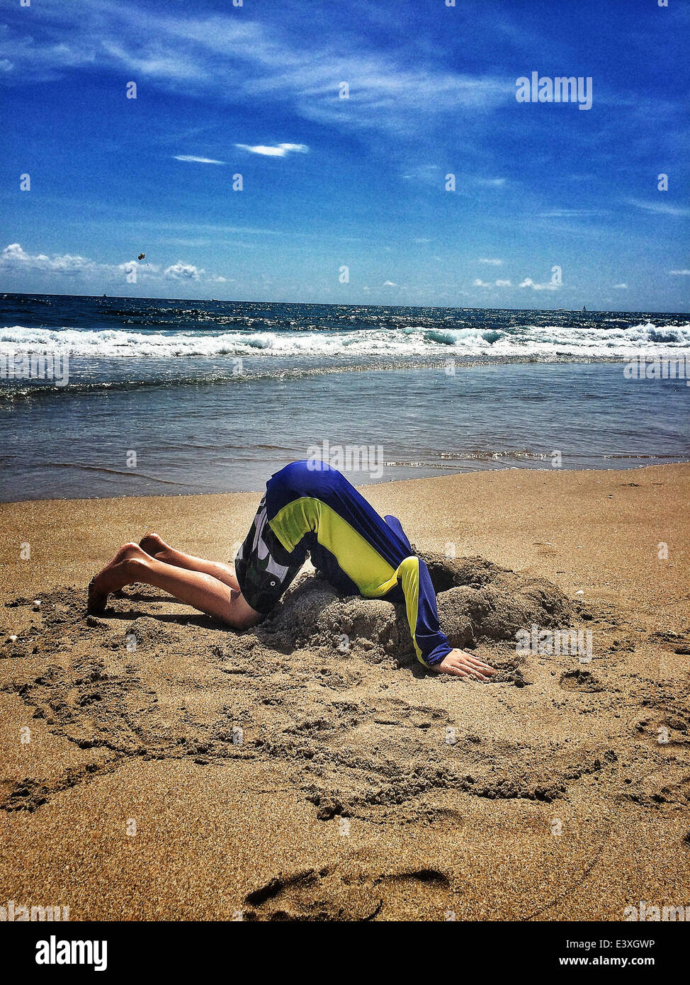 Boy sticking head in sand at beach Stock Photo Alamy
