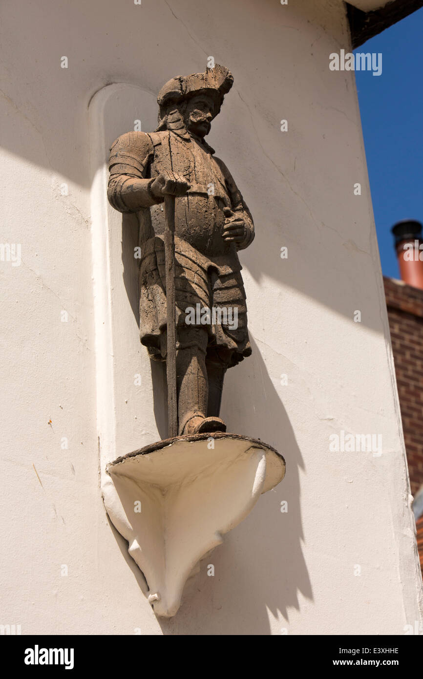 UK England, Suffolk, Lavenham, High Street, historic carved wooden figure on wall above clothes shop Stock Photo